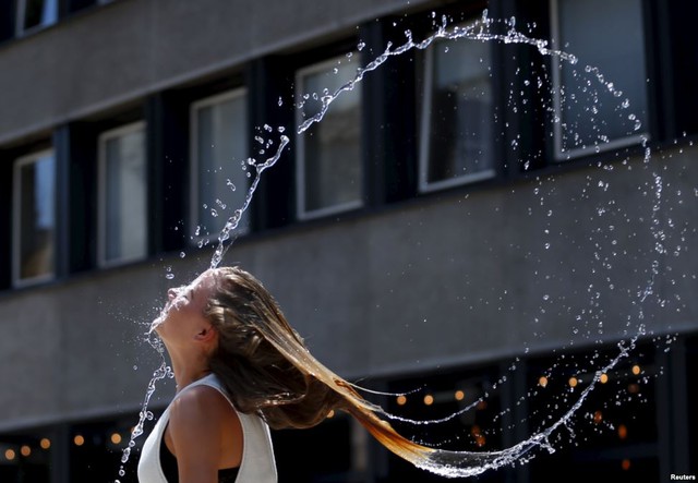 Thiếu nữ vung tóc sau khi nhúng đầu xuống đài phun nước để giải nhiệt tại thành phố Budapest, Hungary.