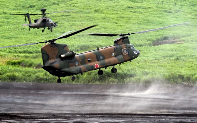 Máy bay vận tải CH-47J Chinook được hộ tống bởi trực thăng tấn công AH-64DJP Apache trong cuộc tập trận bắn đạn thật của Lực lượng phòng vệ Nhật Bản ở Gotemba, gần thủ đô Tokyo.