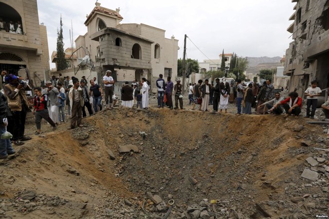 Mọi người đứng quanh một hố lớn tại hiện trường vụ không kích của liên quân do Ả-rập Xê-út đứng đầu tại thành phố Sanaa, Yemen.