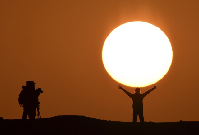 Du khách chụp ảnh trước mặt trời đang mọc tại Khu tự trị Tân Cương, Trung Quốc.