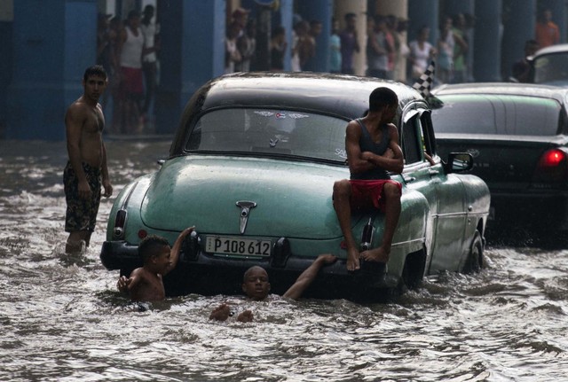 Trẻ em thích thú tắm trên đường phố ngập lụt ở thành phố Havana, Cuba.