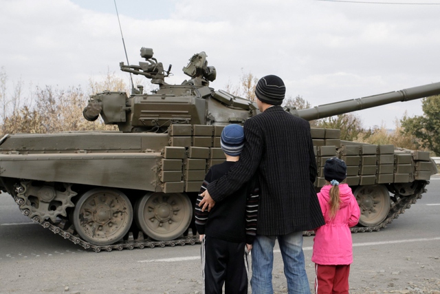 Một gia đình đứng bên đường nhìn xe tăng của phe ly khai thân Nga đi qua ở vùng Lugansk, Ukraine.