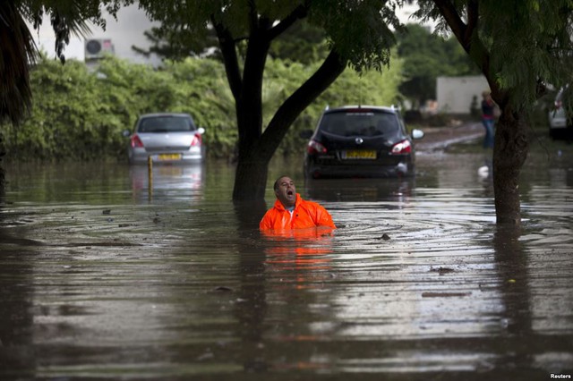 Công nhân cố gắng sửa hệ thống thoát nước trên đường phố ngập lụt ở thành phố Ashkelon, Israel.