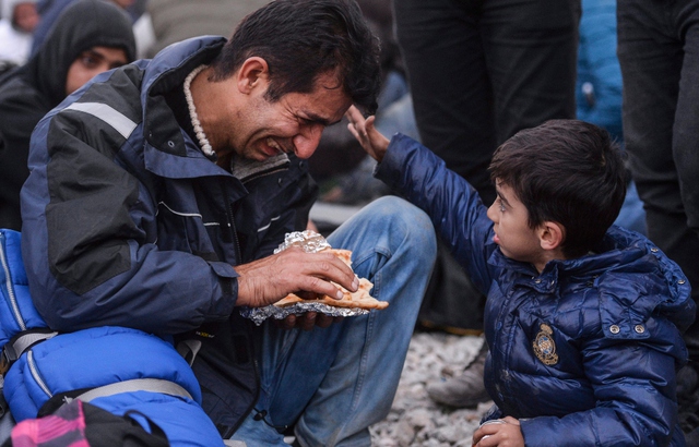 Cậu bé di cư an ủi người bố đang khóc trong cuộc biểu tình gần Gevegelija, Macedonia.