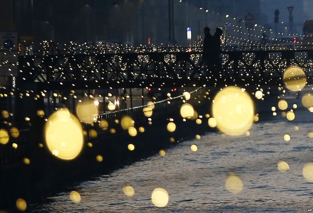 Mọi người đi trên cây cầu bắc qua Darsena dei Navigli dưới ánh sáng lung linh trước lễ Giáng sinh ở Milan, Italia.