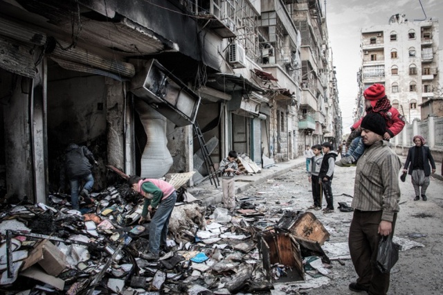 Người đàn ông bế con gái nhỏ trên vai, nhìn đống đổ nát sau cuộc tấn công của quân đội chính phủ nhằm vào thành phố Aleppo, Syria.