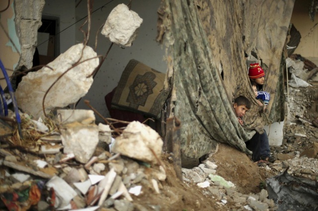 Trẻ em Palestine nhìn ra ngoài từ ngôi nhà đổ nát do bị tàn phàn trong cuộc không kích của Israel vào thành phố Gaza.