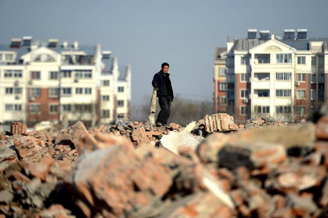 Người đàn ông đứng chờ để nhặt sắt vụn từ những ngôi nhà bị phá bỏ để xây mới tại thành phố Tế Nam, Trung Quốc.