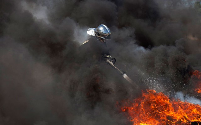 Lính cứu hỏa cố gắng dập tắt lốp cháy do người biểu tình đốt ở ngoại ô thành phố Port-au-Prince, Haiti.