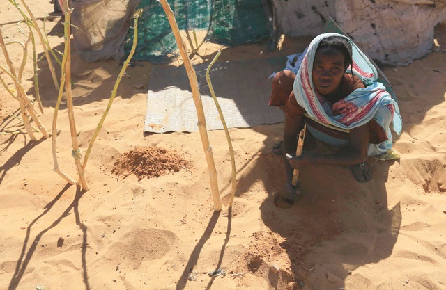 Người phụ nữ đào cát để xây dựng nơi ở tạm tại một trại tị nạn ở North Darfur, Sudan.