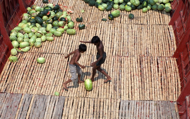 Trẻ chơi đá bóng bằng một quả dưa hấu trên một tàu vận tải dưới sông Buriganga, Bangladesh.