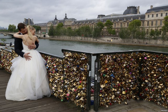 Cặp đôi mới cưới đến từ Ba Lan ôm nhau cạnh những chiếc khóa tình yêu trên cầu Pont de Arts bắc qua sông Seine ở Paris, Pháp.