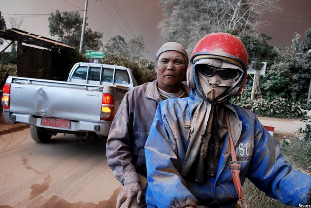 Người đi xe máy bị bảo phủ đầy tro bụi phun trào từ núi lửa Sinabung gần ngôi làng Sukandebi, tỉnh North Sumatra, Indonesia.