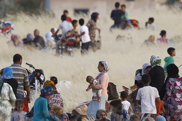 Những người Kurd đến từ thị trấn Kobani của Syria đứng chờ sau hàng rào biên giới để sang thị trấn Suruc, Thổ Nhĩ Kỳ.