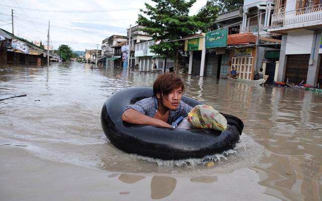 Người đàn ông sử dụng phao hơi để di chuyển qua nước lũ tại thành phố Kalay, vùng Sagaing, Myanmar.