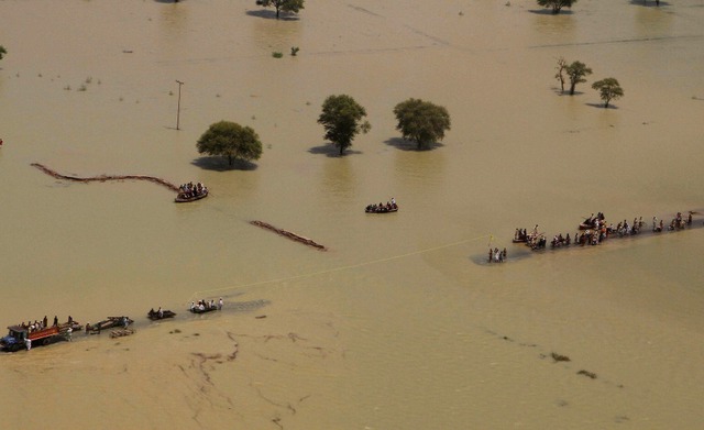 Người dân di chuyển khó khăn trên đường phố ngập lụt tại thành phố Rajanpur, Pakistan.