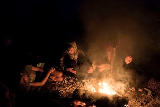 Người tị nạn Syria sưởi ấm quanh một đống lửa trong khi chờ tàu tại một nhà ga ở Idomeni, Hi Lạp.