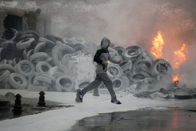 Người đàn ông chạy qua đống lốp xe đang bốc cháy trong cuộc biểu tình của nông dân nuôi bò sữa ở Saint-Lo, Pháp.