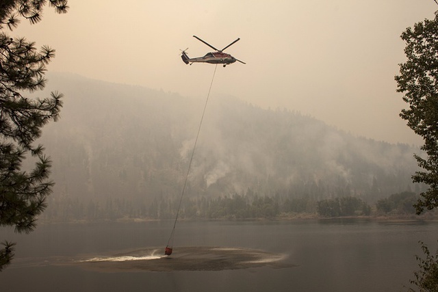Máy bay trực thăng lấy nước dưới hồ trong khi tham gia chữa cháy rừng ở Okanogan, bang Washington, Mỹ.