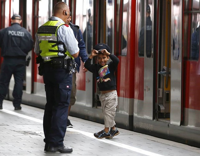 
Một em bé tị nạn đang thử đội chiếc mũ của cảnh sát ở nhà ga ở Munich, Đức ngày 5/9. (Nguồn: CCTVNews)
