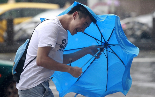 Người đàn ông cầm ô đi dưới mưa và gió lớn do bão Dujuan gây ra tại thành phố Đài Bắc, Đài Loan.