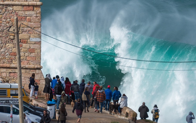 Du khách ngắm những đợt sóng cao đánh vào bờ biển ở Praia do Norte in Nazaré, Bồ Đào Nha.