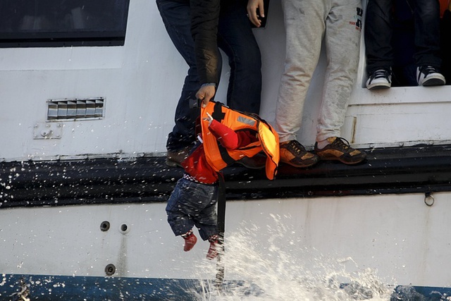 Nhân viên cứu hộ đưa một em bé di cư bị ngã xuống nước lên tàu ở ngoài khơi đảo Lesbos, Hi Lạp.