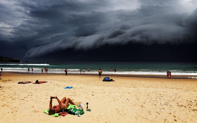 Mọi người nằm tắm nắng trên bãi biển khi mây đen đang dần bao phủ bầu trời thành phố Sydney, Australia.