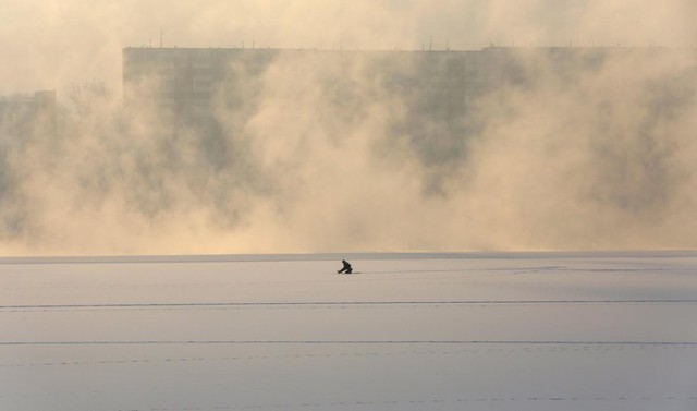 Người đàn ông câu cá trên mặt nước đóng băng tại sông Yenisei dưới nhiệt độ lạnh -4 độ C ở thành phố Krasnoyarsk, Nga.