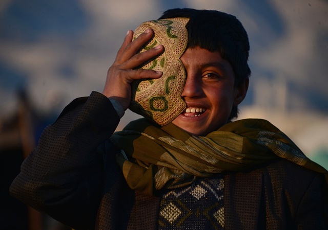 Cậu bé cười rạng rỡ khi đừng gần căn lều của mình ở ngoại ô Herat, Afghanistan.