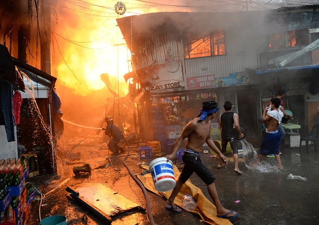Lính cứu hỏa và người dân cố gắng dập tắt đám cháy tại một khu ổ chuột ở Manila, Philippines.