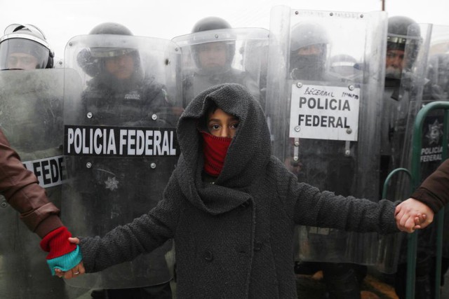 Em bé cầm tay người biểu tình chống chính phủ trong khi đứng trước cảnh sát ở thành phố Ciudad Juarez, Mexico.