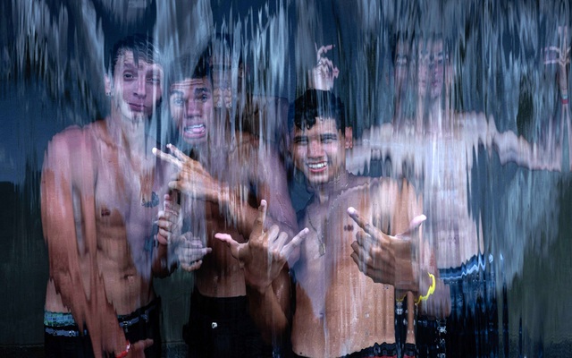 Các nam thiếu niên chụp ảnh khi đứng sau màn nước tại công viên Madureira ở Rio de Janeiro, Brazil.