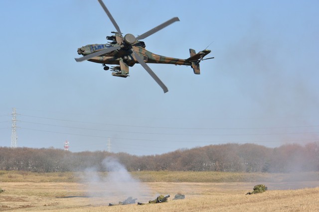 Một chiếc trực thăng AH-64 bay trên lực lượng bộ binh đang ở vị trí chiến đấu.