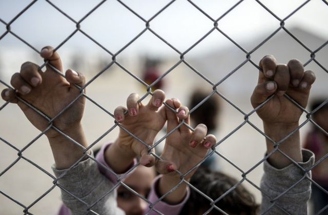 Trẻ em tị nạn người Syria bấu tay vào hàng rào tại một trại tị nạn của Liên Hợp Quốc ở Sanliurfa, Thổ Nhĩ Kỳ.