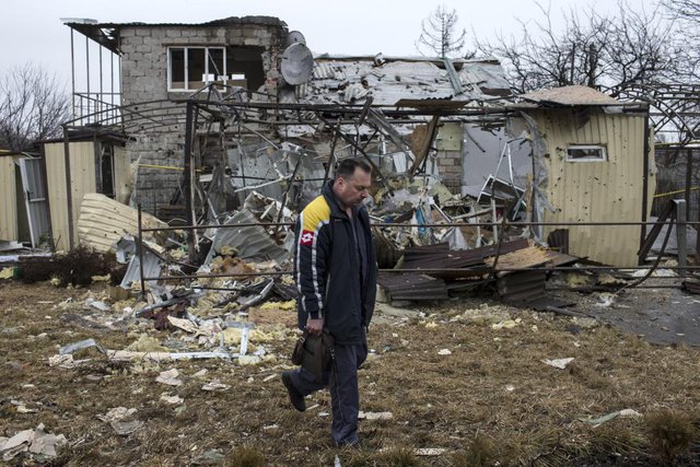 Người đàn ông đi qua ngôi nhà bị phá hủy tại một khu dân cư ở Donetsk, Ukraine.