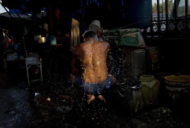 Người đàn ông vô gia cư tắm trên đường phố ở New Delhi, Ấn Độ.