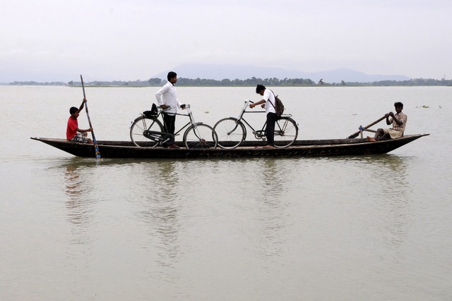 Học sinh được chở bằng thuyền qua một cánh đồng ngập lụt ở Assam, Ấn Độ.