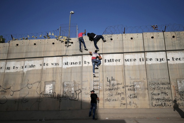 Những người Palestine cố gắng trèo qua bức tường bê tông để vào thành phố Jerusalem từ Bờ Tây.