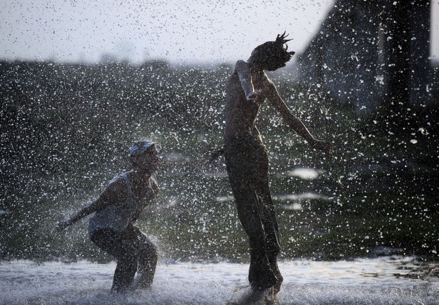 Mọi người thích thú tắm mát dưới đường ống nước bị vỡ trong một ngày nắng nóng ở Karachi, Pakistan.