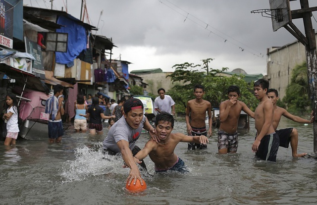 Người dân chơi bóng rổ trên đường ngập lụt do mưa bão tại thành phố Malabon, Philippines.