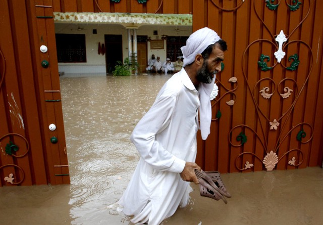 Người đàn ông lội qua đoạn đường ngập lụt sau nhiều ngày mưa lớn ở Peshawar, Pakistan.