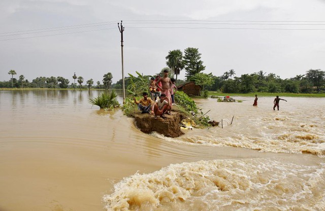 Người dân ngồi trên một đoạn đê bị vỡ do nước lũ tại bang Tây Bengal, Ấn Độ.