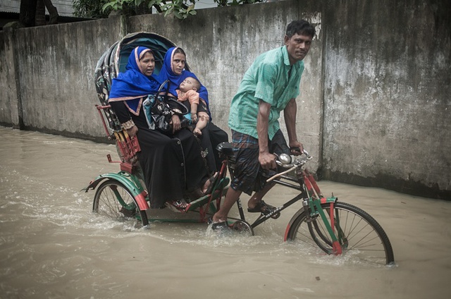 Người đàn ông đạp xe ba bánh chở khách qua đoạn đường ngập nước ở Chittagong, Bangladesh.