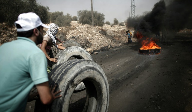 
Người biểu tình Palestine lăn lốp xe để làm tường lửa trong cuộc đụng độ với binh sĩ Israel tại ngôi làng Kfar Qaddum, Bờ Tây. 
