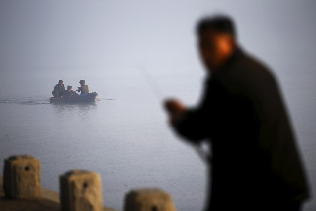 
Một người đàn ông đang bắt cá trong khi một nhóm sĩ quan quân đội Triều Tiên chèo một chiếc thuyền nhỏ trên sông Taedong ở Bình Nhưỡng trong buổi sáng sớm mù sương ngày 8.10.
