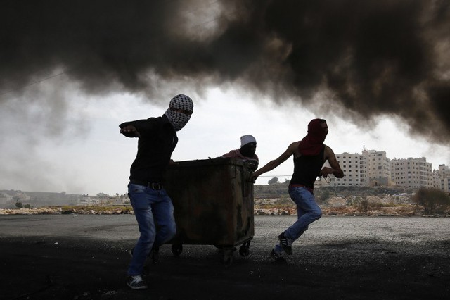 Người biểu tình Palestine kéo thùng rác trong khi đụng độ với lực lượng an ninh Israel tại thị trấn Al-Bireh, Bờ Tây.