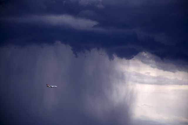 Chiếc máy bay Boeing 737-800 của hãng hàng không Qantas di chuyển qua đám mây bão đen kịt trên bầu trời Sydney, Australia.