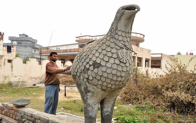 
Một người đàn ông đang trang trí cho chiếc bể chứa nước hình đại bàng.
