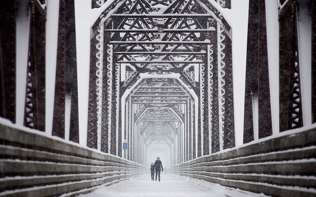 Mọi người đi dưới mưa tuyết dọc một cây cầu ở thành phố Fredericton, Canada.